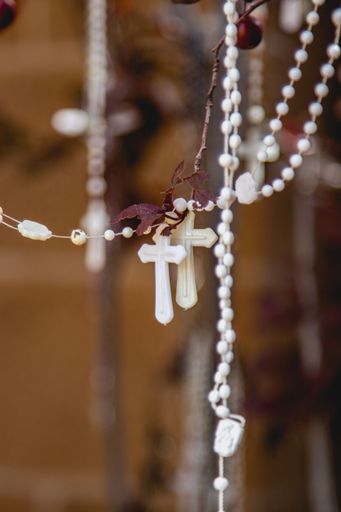 A vertical closeup of white Catholic rosary beads hanging from tree branches in Santa Fe, New Mexico