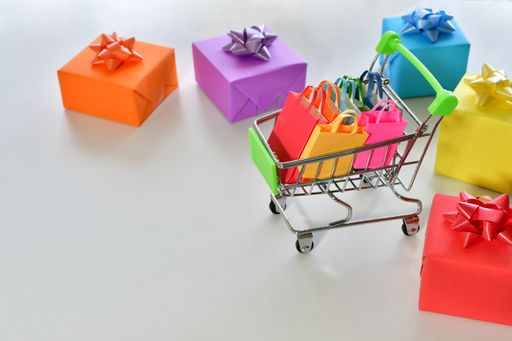 A closeup shot of gift boxes and a shopping cart filled with colorful paper bags