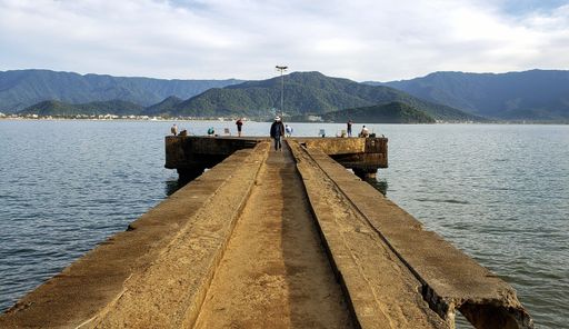 Several people on a bridge over the sea with hills in the background in Sao Paulo, Brazil