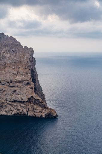 A vertical shot of the rocky cliffs over the Mallorca Mediterranean Sea captured in Spain