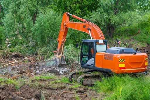 Powerful orange excavator with help of crusher rig crushes reinforced concrete structures to clean metal reinforcement.