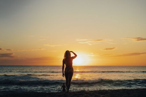 A beautiful shot of a woman in a bikini on the beach during a sunset