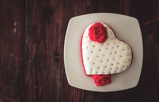 A top view of a plate with a romantic heart-shaped pastry with marizpan red roses