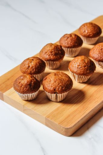 A vertical closeup shot of a wooden board with homemade delicious brown muffins