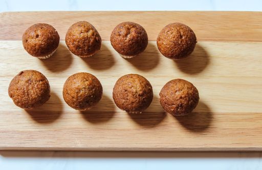 A closeup shot of a wooden board with homemade delicious brown muffins