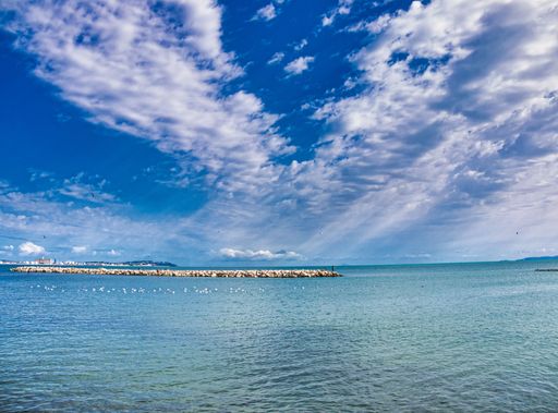 A beautiful shot of a small island covered in stones in the middle of a lake under the blue cloudy sky