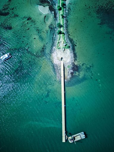 An aerial view of a boat near the pier on the sea full of corals