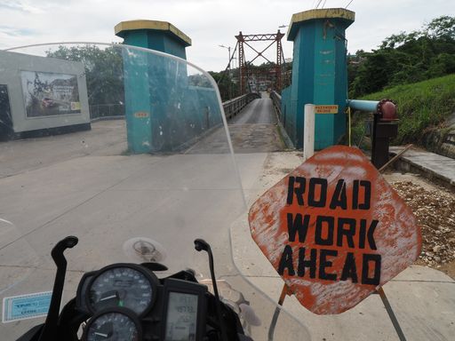 A closeup shot of a rusty Road Work Ahead sign on the road