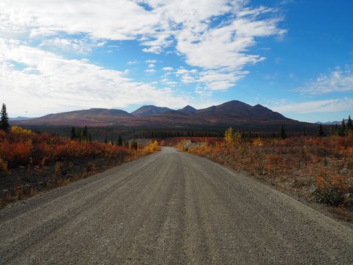 A beautiful scenery of a pathway surrounded by high rocky mountains under a cloudy sky