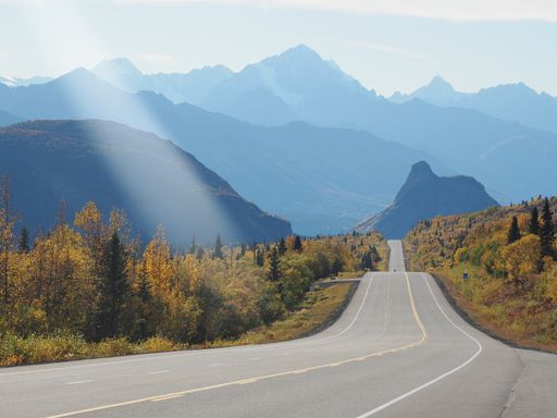 A beautiful scenery of a pathway surrounded by high rocky mountains under a cloudy sky