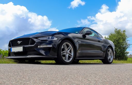 Black sports car in front of a northern germany landscapes on a sunny day in Germany