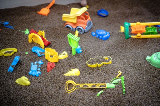 A close-up sot of plastic kids toys on black sand