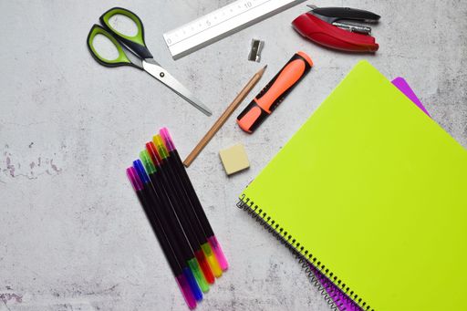 A top view of assorted necessary school supplies on grunge wall background