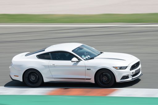 A stunning white Ford Mustang racing around on a competition track