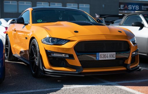 An impressive orange Ford Mustang parked on the side of a street