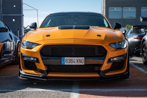 An impressive orange Ford Mustang parked at an exhibition