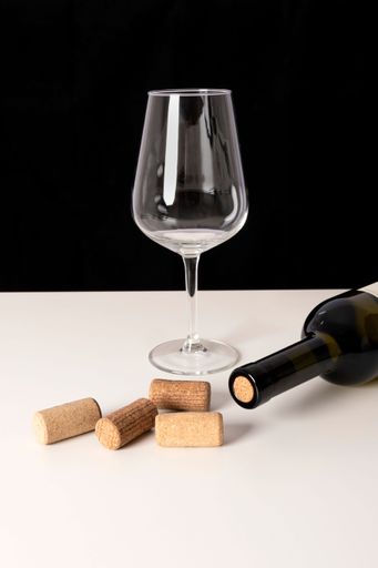 A vertical shot of a wine bottle, glass with wooden corks on the table