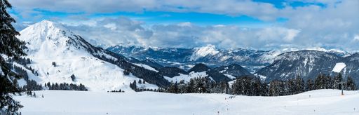 A panoramic shot of a mountainous area covered with snow on a beautiful day