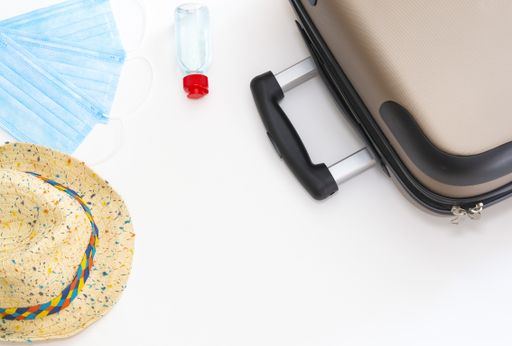 A top view of a suitcase with facemasks, hand sanitizer and a hat isolated on a white background - COVID-19