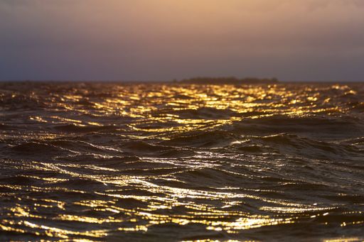 A view of the vast ocean water with glimmers of sunlight on the surface