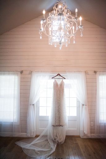 A vertical shot of a wedding dress hanging on a cornice
