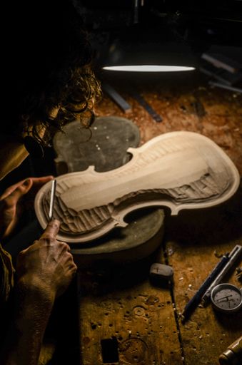 hands of artisan woman violin maker luthier working in the back table of a new hand made cremonese violin