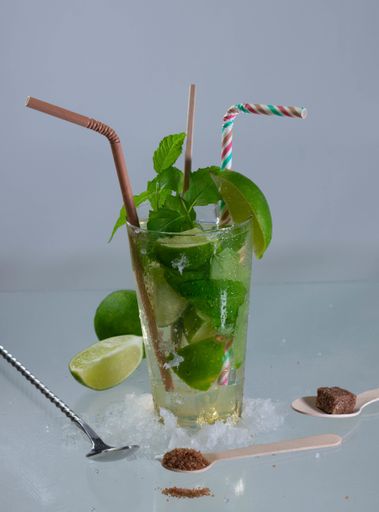 A vertical shot of a mojito cocktail with rum, lime and mint leaves on a gray surface