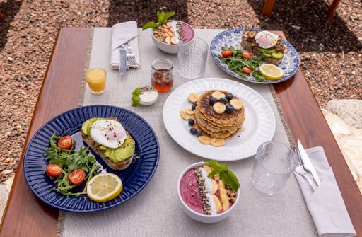 A high angle shot of a delicious brunch with pancakes and avocado toast served on a wooden table.