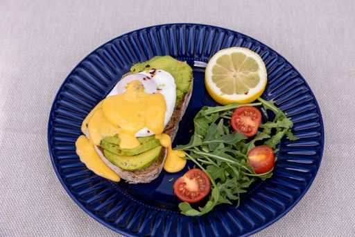 A high angle of an avocado toast with salad served on a blue plate.