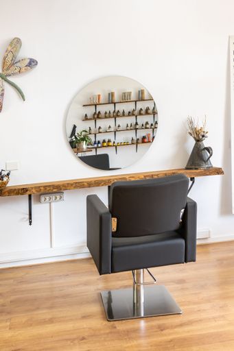 A modern chair and round mirror on a white wall in a room