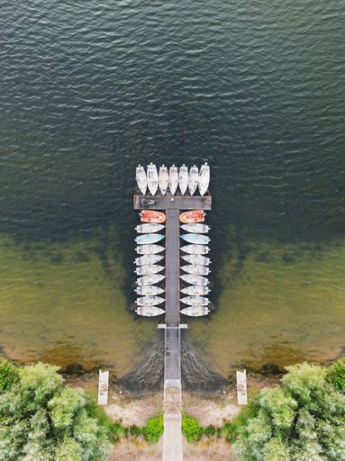 A beautiful view of docked boats with a pier on an island with trees