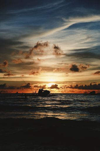 A vertical shot of a vibrant, colorful sunset in the cloudy sky over the ocean