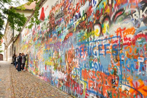A group of young people paint a graffiti on the John Lennon Wall in Prague, Czech Republic