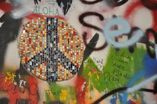A closeup shot of a graffiti and peace sign mosaic at the John Lennon Wall in Prague, Czech Republic