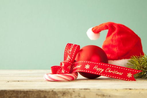 A closeup of Christmas ornaments and a candy cane on a wooden table under the lights