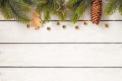 A top view shot of Christmas tree branches with gold ornaments and a pine cone on a white background