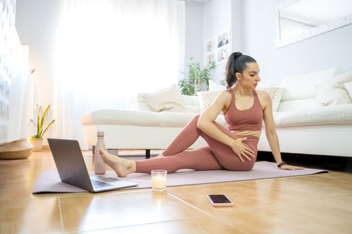 YOUNG GIRL DOING YOGA AND PILATES IN THE LIVING ROOM OF HER HOME WITH THE COMPUTER very happy