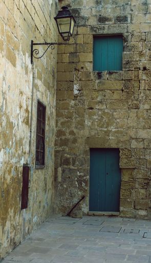 A long shot of a building with blue doors and a street lamp in Malta