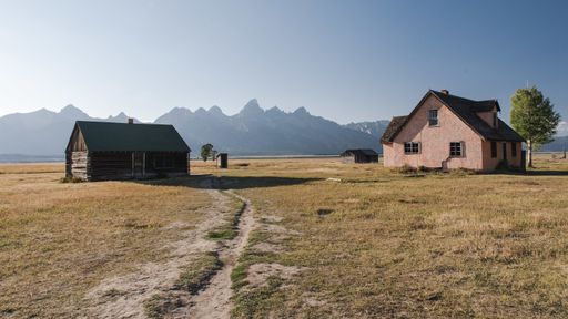 Two old houses in the rural area with mountains on the background