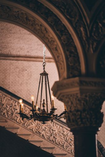 A vertical shot of antique chandelier with candles illuminating a beautiful building with columns