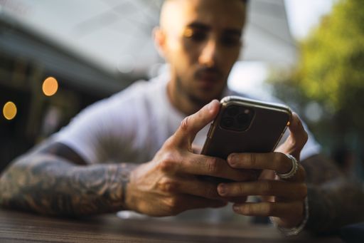 A selective focus shot of a male holding a phone in a restaurant