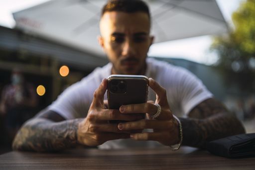 A selective focus shot of a male holding a phone in a restaurant