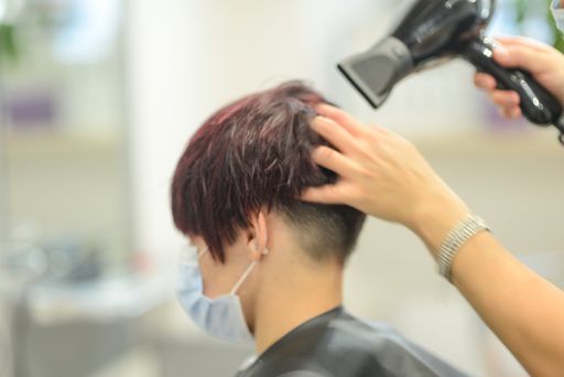 A closeup shot of a female getting her hair done while wearing a sanitary mask - the new normal concept