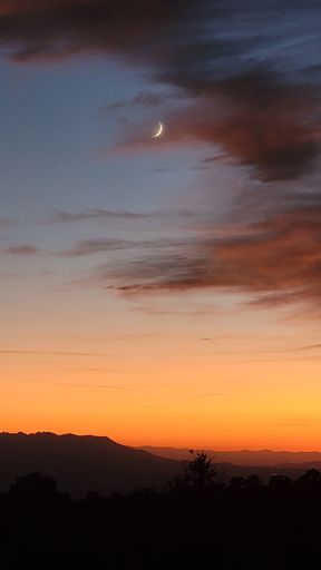 A vertical shot of the dramatic sunset with the moon crescent in Lovell Canyon road, Nevada, USA
