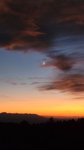 A vertical shot of the dramatic sunset with the moon crescent in Lovell Canyon road, Nevada, USA