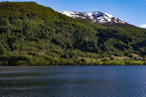 A beautiful view of a calm lake and forested mountains in Vestland, Norway, on a sunny day