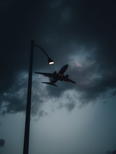 A vertical shot of a light pole against the background of the cloudy sky with an airplane. Chicago.