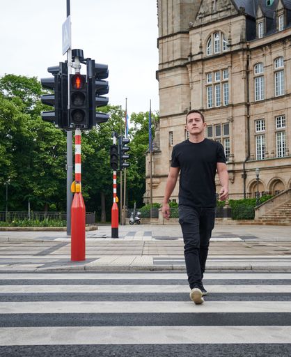 A vertical shot of a man crossing a street in front of State Savings Bank, Luxembourg