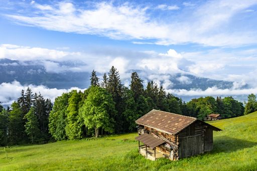 The image shows a hut on the mountainside overlooking a valley filled with the early morning fog