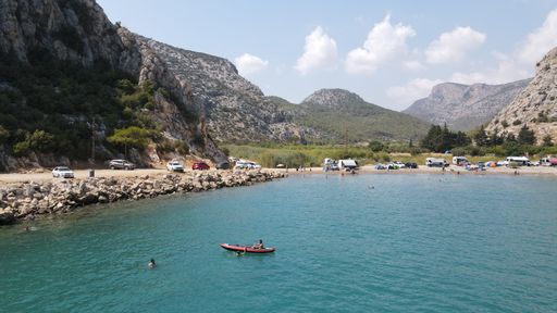 An aerial view of people sailing and swimming in a beautiful cove with clear water on a sunny day